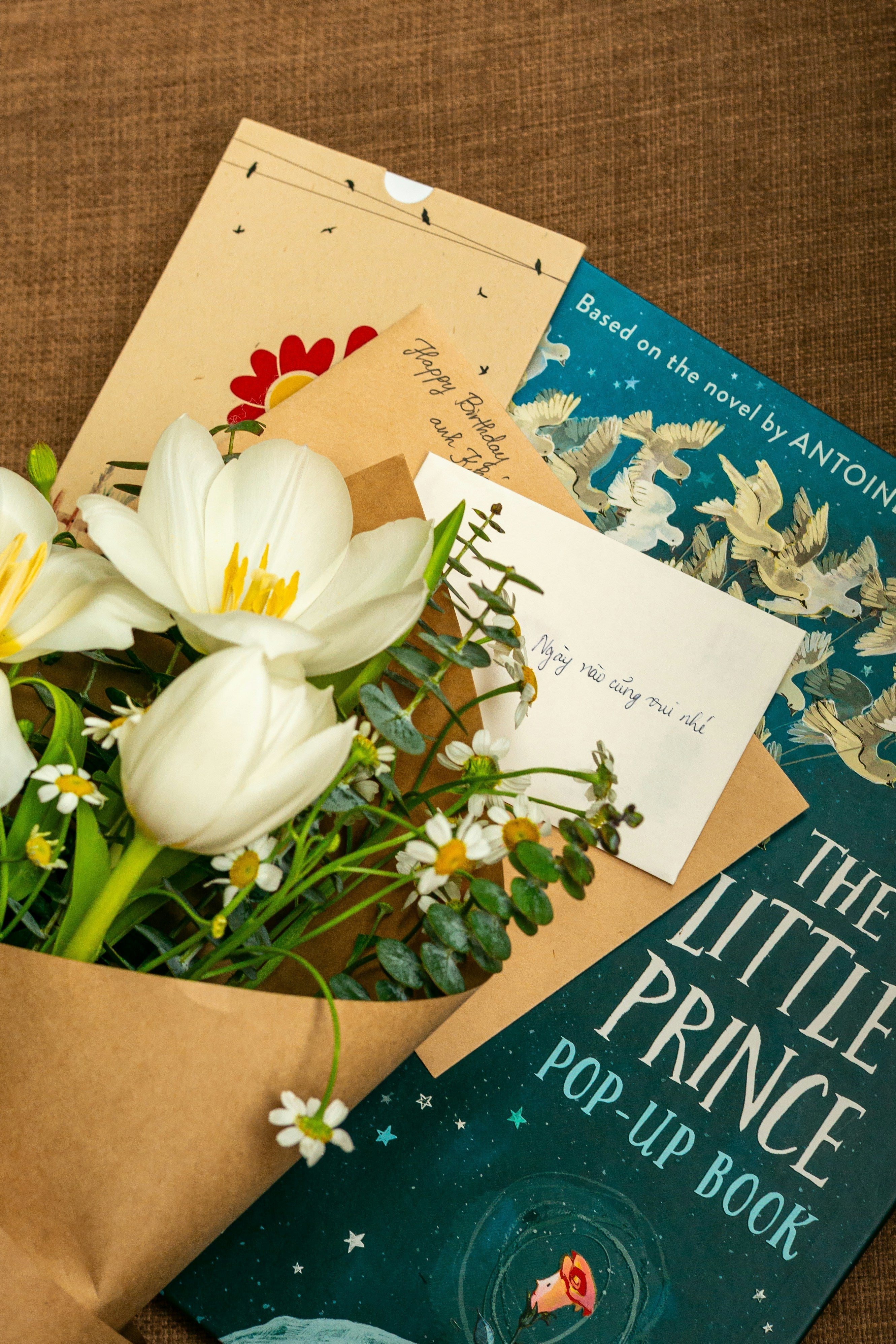 Ein Blumenstrauss mit einer Geschenkkarte und einem Geschenkbuch
